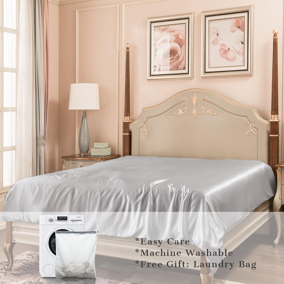 A silver mulberry silk bed sheet on a bed in a bedroom interior, with a laundry bag and washing machine graphic overlay and text 'Easy Care'
