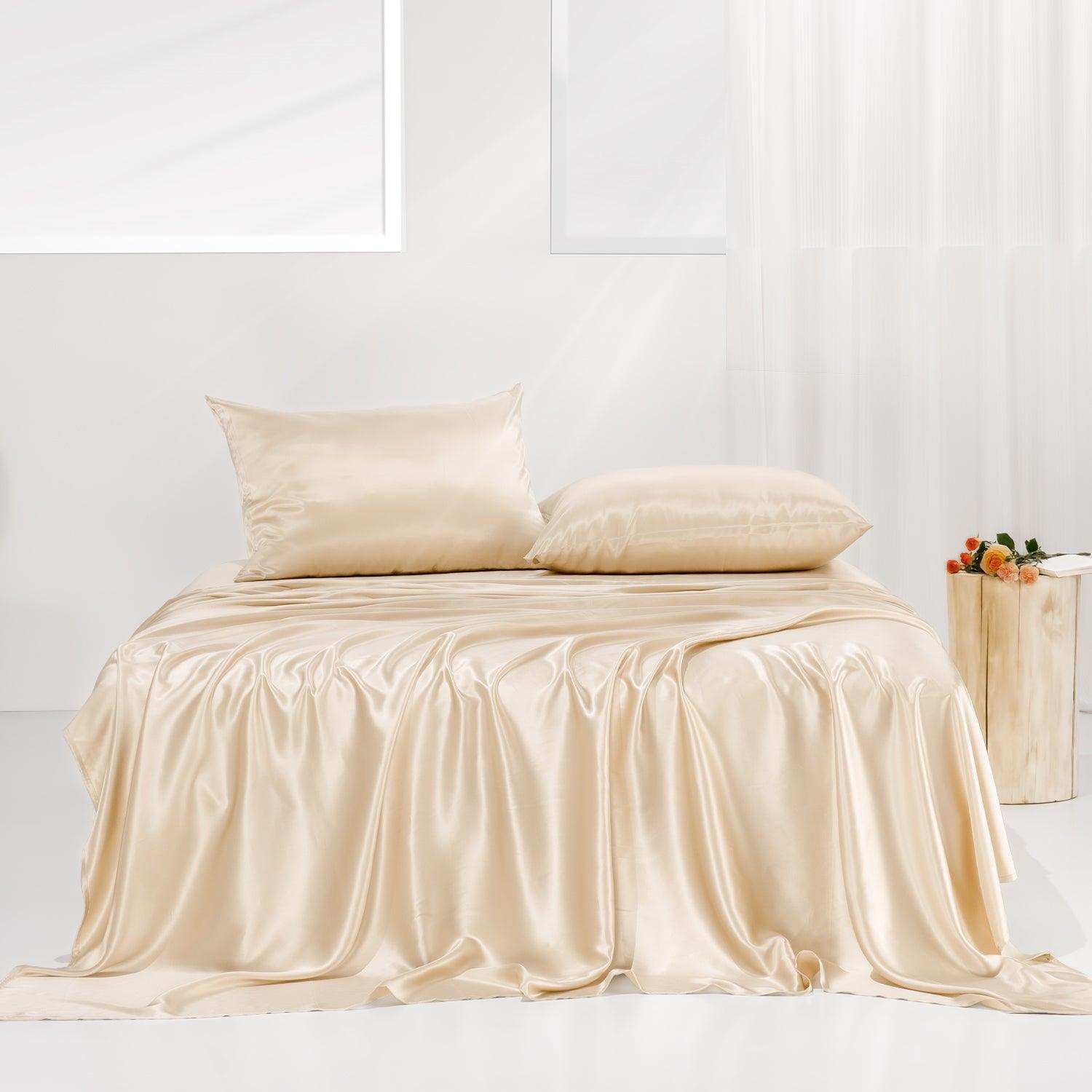 A beige mulberry silk bed sheet set arranged in a flatlay on a plain studio backdrop, showcasing a smooth, lustrous sheen.